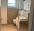 Modernes Badezimmer mit WC, Waschbecken auf Holzunterschrank und Duschkabine aus Glas.