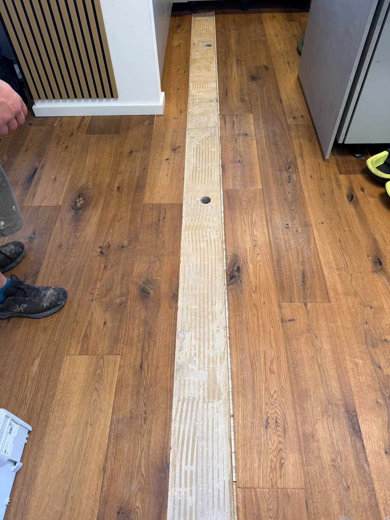 Herausgenommene Diele, darunter das gerillte Kleberbett auf dem Estrich