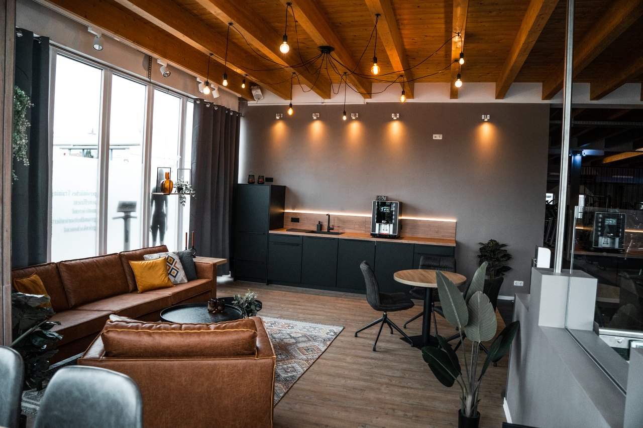 Moderne Lounge mit braunen Ledersofas und Holzbalkendecke.