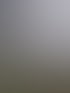 Eine beige Panasonic Klimaanlage hängt an einer weißen Hauswand über einem Kiesbeet.