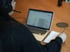 Therapeutin mit Headset schreibt Notizen auf Block, Laptopbildschirm unscharf zu sehen