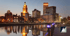 Providence, Rhode Island skyline at dusk, with city lights reflecting on the river and a boat logo in the corner.