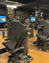 Moderne Fitnessgeräte mit Bildschirmen und Holzboden in einem Fitnessstudio.