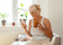 Frau hält mit einer Hand eine Tasse Kaffee in der Hand und mit ihrer anderen, tippt sie auf ihrem Handy 