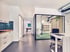 Modernes Büro mit Küchenzeile, Schreibtischen, Glaswänden und Lüftungsrohren an der Decke.