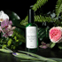 Grüne Sprühflasche "Rose Hydrolat, Rosa damascena flower water BIO 100 ml" umgeben von Blumen und Farnen - AROMA WOMYN