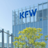 Modernes Bürogebäude mit der Aufschrift „KFW“ und einem Baum im Vordergrund.