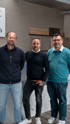 Mann in blauem Weber Polo-Shirt lächelt, Team und gelbe Transporter im Hintergrund.
