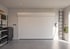 Moderne Garage mit weißem Rolltor, Regalen, Werkzeugkiste und einer Ladestation für Elektroautos.
