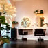 Moderner Friseursalon in Bonn mit zwei leeren Stühlen, runden Spiegeln und einem weißen Kunstbaum mit Blüten.