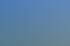Frau mit Schal und Jeans steht auf einer grünen Wiese unter einem weiten blauen Himmel mit Wolken.
