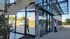 Glasreiniger säubert die hohen Fensterfronten und das Glasvordach eines Bürogebäudes mit einer Teleskopstange.