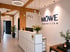 Rezeption mit weißem Tresen, blauem "MÖWE IMMOBILIEN"-Logo an weißer Wand und Holzbalken.
