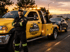 Towing Eastvale operator standing beside a tow truck while providing roadside towing service for a disabled vehicle at sunset