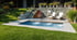 Hinterhof mit rechteckigem Pool, Grasflächen, Steinstufen, zwei weißen Liegestühlen und einer Steinmauer.