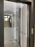 Moderner Aufzug mit offenen Türen, Edelstahl-Bedienfeld und Handläufen, dahinter Treppe.