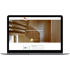 Laptop zeigt die Webseite der Holzbau Baumer GmbH mit einer hölzernen Treppe und modernem Innenausbau aus Holz.