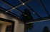 Beleuchtetes Terrassendach aus Glas und Aluminium mit integrierten LED-Spots und Lichtleisten bei Nacht.