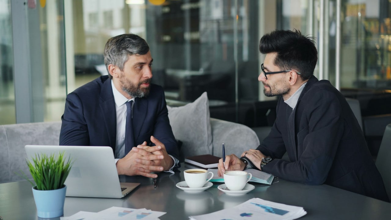 Zwei Männer im Mentoring-Gespräch an einem Tisch