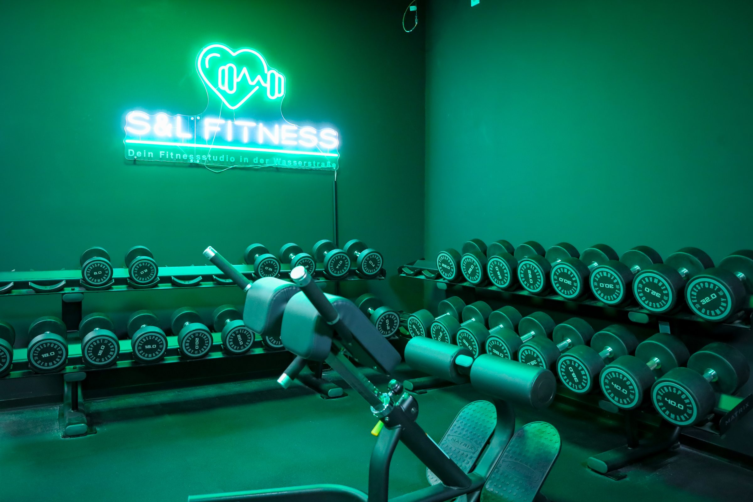 Kurzhantelbereich unter dem S&L Fitness Neonschild