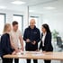 Vier Kollegen besprechen Dokumente und Diagramme an einem Konferenztisch.