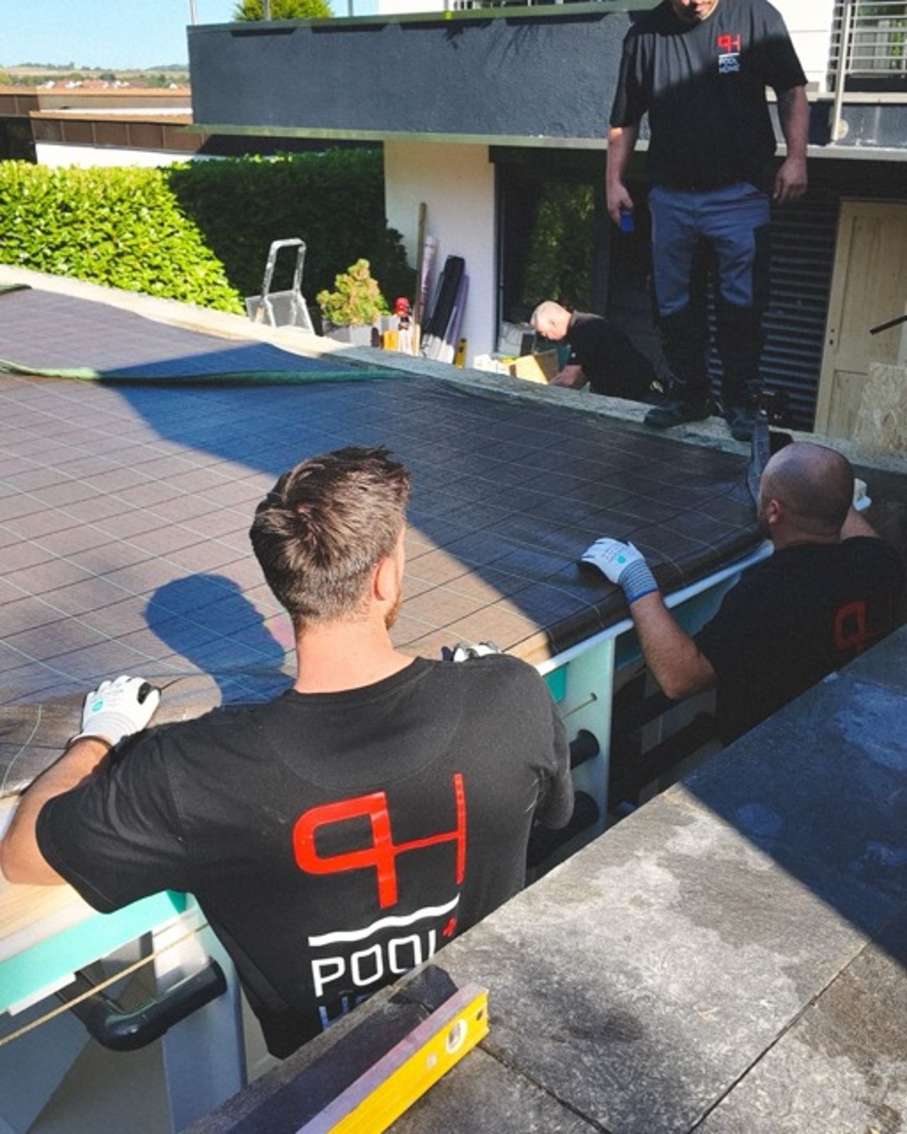 Drei Kollegen installieren die Poolabdeckung