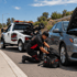 Towing Corona roadside assistance technician repairing a disabled car on the roadside with a service truck nearby.