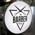 Rundes, leuchtendes Schild mit schwarzem Logo: Schere über "THE BARBER TANDRAGEE EST 2010".
