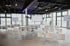 Moderner Konferenzraum mit weißen Stühlen, Tischen, großen Glasfronten und Leinwänden unter einer dunklen Decke mit Lichterketten.