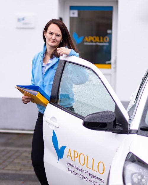 Apollo-Mitarbeiterin am Einsatzfahrzeug vor dem Büro