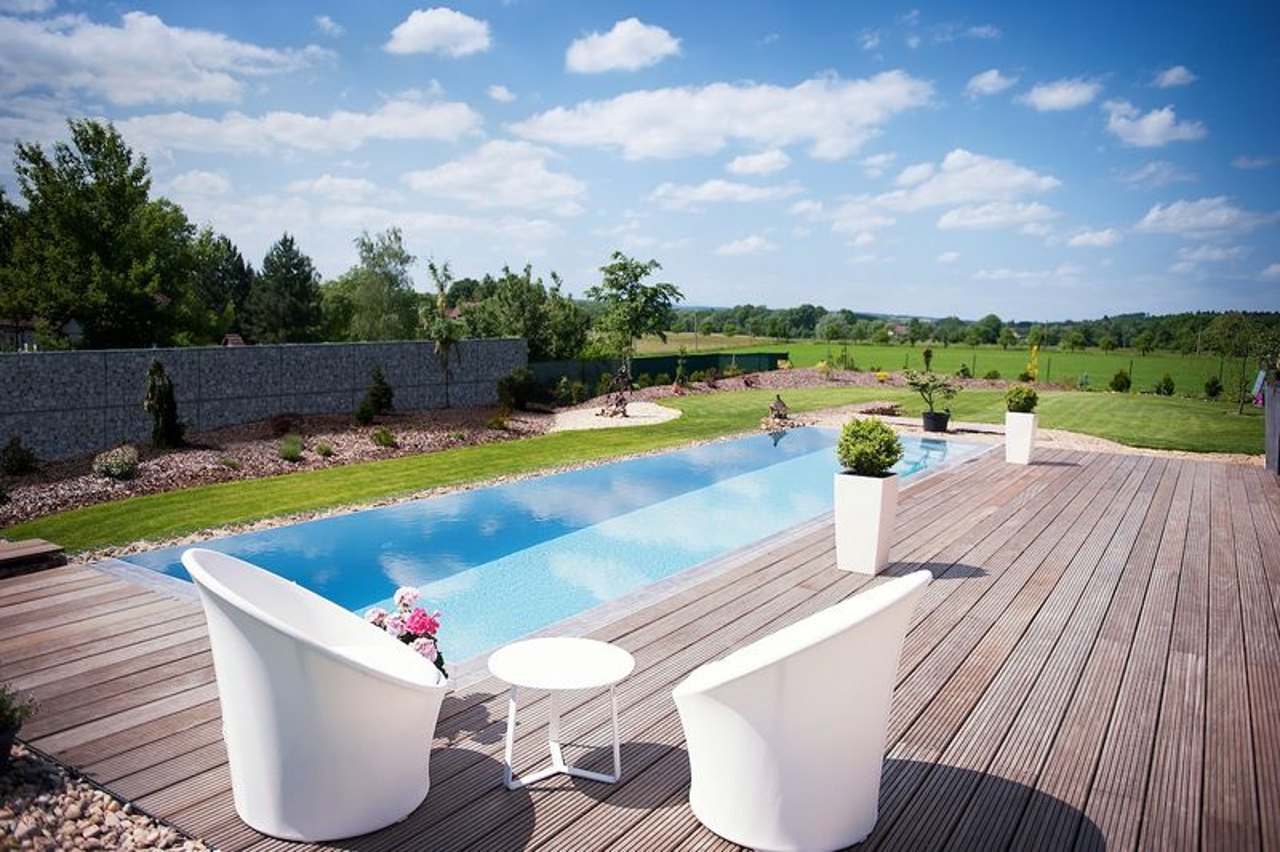 Langer schmaler Pool mit Holzterrasse und Gartenmöbeln