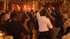 Menschen tanzen auf einer Weihnachtsfeier mit DJ, festlicher Beleuchtung und einem geschmückten Tannenbaum im Hintergrund.
