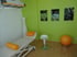 Ein Fitnessstudio mit Holzboden, Trainingsgeräten, Sprossenwand und einer Küchenzeile.
