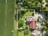 Luftaufnahme eines L-förmigen Grundstücks mit Rasen und Bäumen neben einem Feld und Gebäuden.