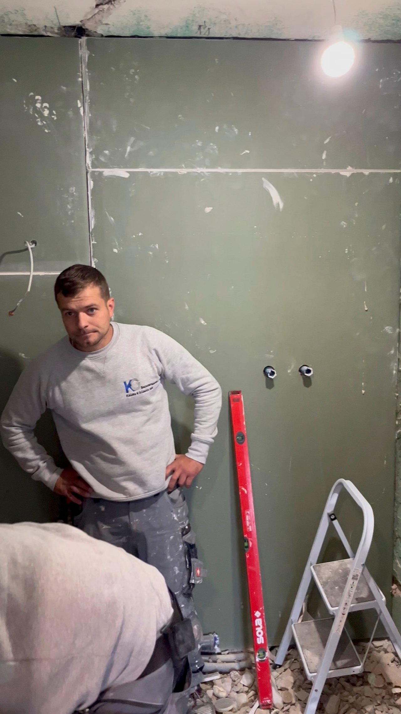 Facharbeiter von K&G Bauunternehmen prüft eine Wand mit der Wasserwaage