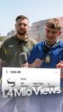 Ein lachender Mann mit Bart telefoniert mit einem Smartphone und hält sich die Ohren zu.