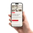 Hand hält Smartphone mit der VELUX App „Erstellen Sie Ihr Traumfenster“ auf dem Bildschirm.