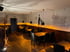 Innenansicht eines Restaurants mit dunklen Holztischen, schwarzen Stühlen und einer Charlie-Chaplin-Silhouette an der Wand.