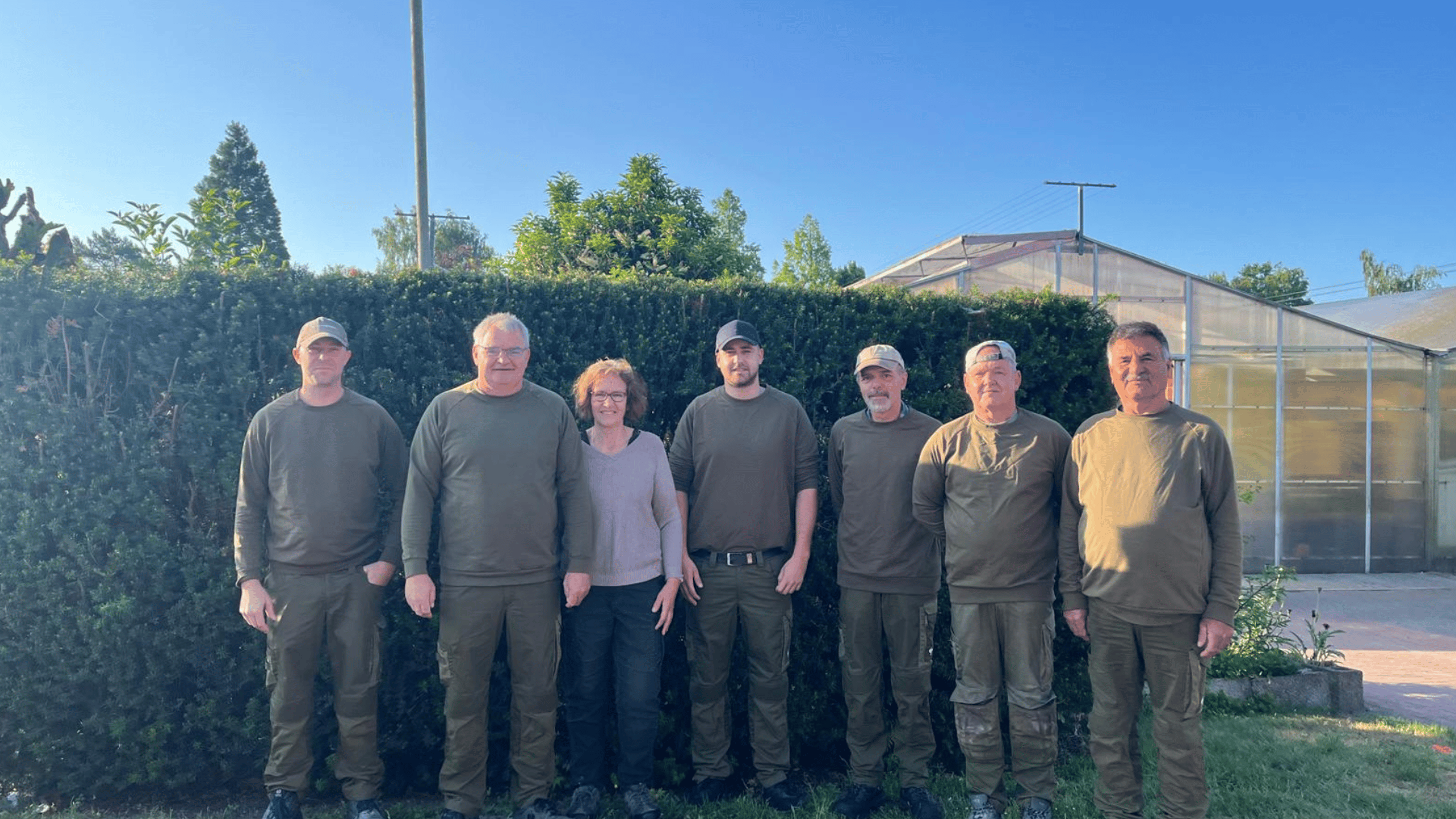 Das Team von Siefken Pflanzen in grüner Arbeitskleidung vor einer Hecke