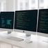Drei Apple iMac-Monitore auf einem Schreibtisch; der linke zeigt Diagramme, die anderen Code.