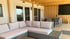 Gemütliche Holzterrasse mit einem L-förmigen Sofa und einem Esstisch mit Stühlen im Mobilheim Villa Aperol.