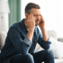 Man clutching his temples indoors, suffering from a headache