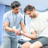 A therapist helps a man lift a dumbbell during rehab exercises
