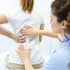 A physical therapist examining a patient's lower back pain.