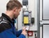 Techniker bedient eine industrielle Torsteuerung per Smartphone-App neben einem installierten Steuerungsmodul an der Wand.
