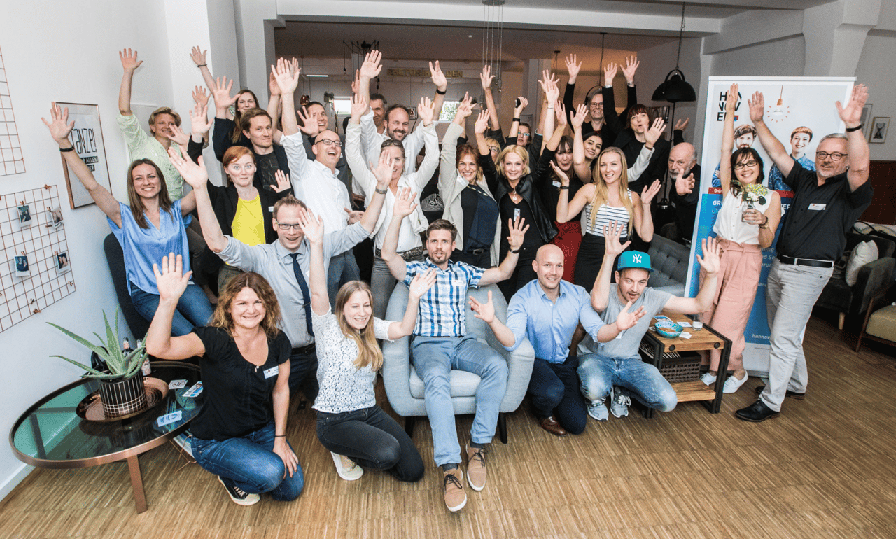Gut gelaunte Gruppe mit erhobenen Armen im Loft der NEOP Academy Hannover