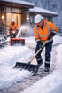 Zwei Männer räumen Schnee: Einer schaufelt einen Weg, der andere bedient eine Schneefräse vor einem Haus.