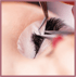 Nahaufnahme einer Person, die mit einer Pinzette künstliche Wimpern anbringt.
