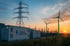 Container mit "ENERGIE VERSORGUNG", Strommasten und Windräder bei Sonnenuntergang - Software-KRITIS Notfall- und Krisenmanager (NKM®).