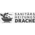 Grauer Drache in einer Badewanne, speit Flammen, neben dem Text "SANITÄR & HEIZUNGS DRACHE".